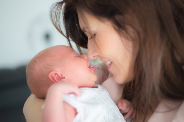 sesja noworodkowa łodź uśmiechnięta mama patrzy na noworodka z wysuniętym języczkiem
