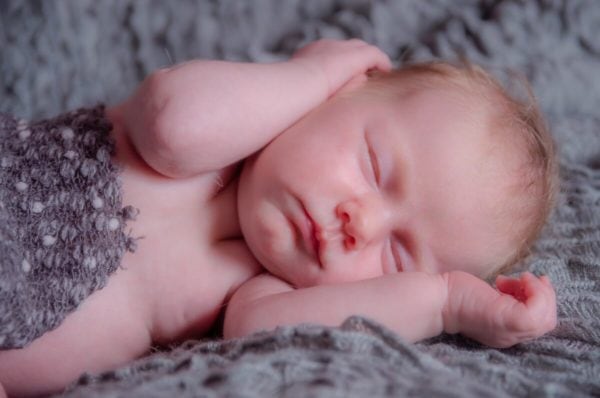 łódź sesja noworodkowa domowa noworodek śpiący na boku z ręką na głowie
