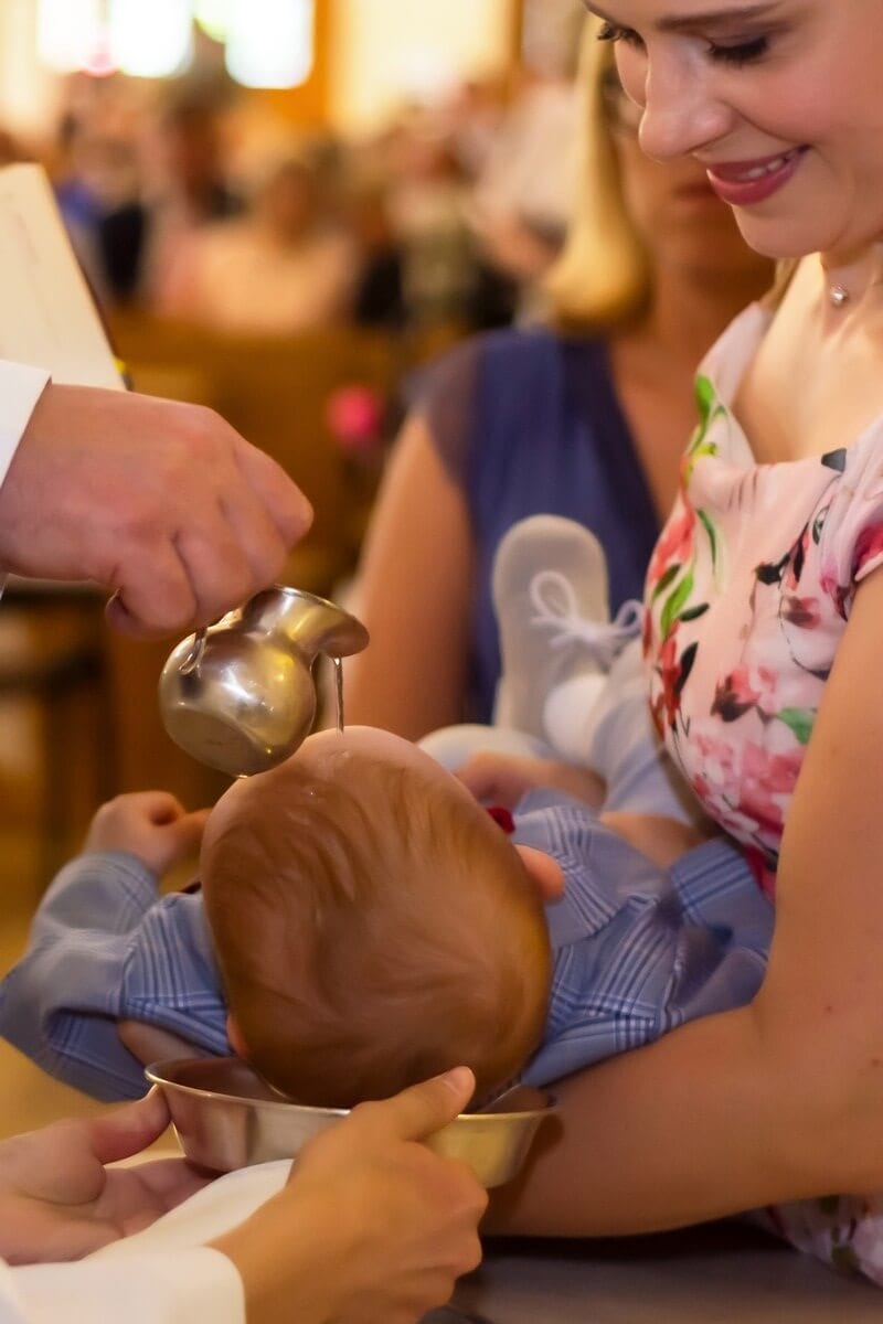 Zdjęcia z chrztu Łódź reportaż z chrztu w kościele polewanie główki chłopca mama patrzy się na dziecko i uśmiecha SZ19
