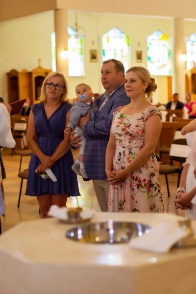 Zdjęcia z chrztu Łódź reportaż z chrztu w kościele rodzice stoją przy chrzcielnicy SZ20