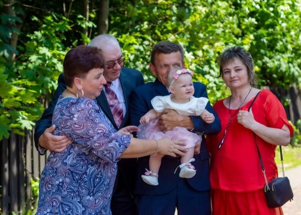 Zdjęcia z chrztu Łódź reportaż dziadkowie z wnuczką na tle drewnianego płotku