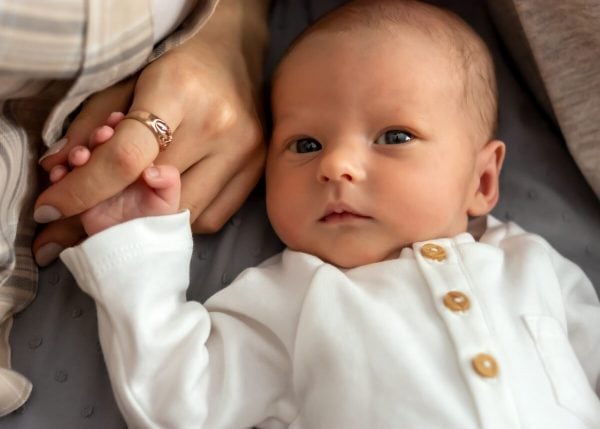 naturalna fotografia noworodkowa Łódź noworodek leży na plecach i trzyma mamę za palec