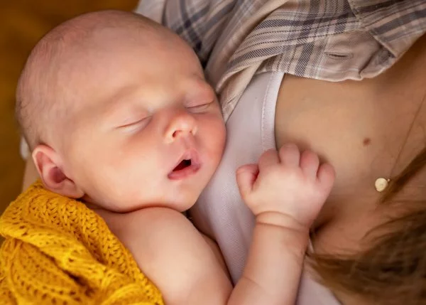 naturalna fotografia noworodkowa Łódź noworodek na piersi mamy śpi z otwartymi ustami