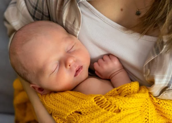 naturalna fotografia noworodkowa Łódź noworodek śpi przytulony do piersi matkiersi